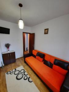 a living room with an orange couch and a rug at Happy apartament in Sibiu