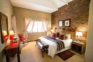 a bedroom with a large bed and a brick wall at Downstream in Dullstroom