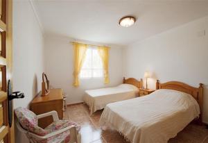 a bedroom with two beds and a chair and a window at La Casa Del Sol in Torrevieja