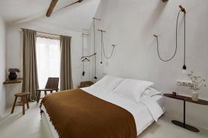 - une chambre avec un grand lit aux murs blancs dans l'établissement La Maison de Pommard, à Pommard