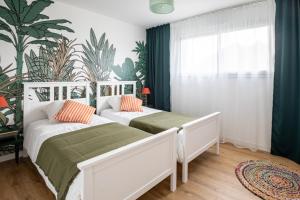two beds in a bedroom with green and white at La Fée - jolie maison avec jardin - plage à 700 m in Dinard