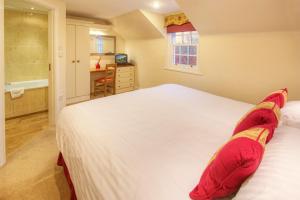 ein Schlafzimmer mit einem großen weißen Bett mit roten Kissen in der Unterkunft Pol!cehouse Cottages, Embleton in Alnwick