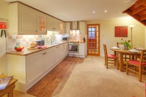 eine Küche mit weißen Schränken und einem Tisch darin in der Unterkunft Pol!cehouse Cottages, Embleton in Alnwick