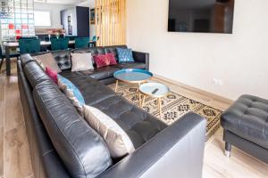 a living room with a black leather couch at La Fée - jolie maison avec jardin - plage à 700 m in Dinard