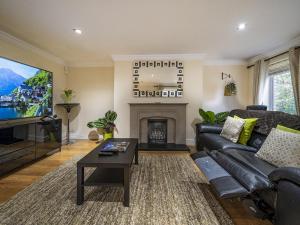 a living room with a black leather couch and a tv at Pass the Keys Fab Townhouse Near Queens with Huge TV & Recliners in Belfast