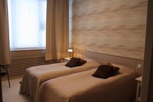 two beds in a hotel room with a large window at Ruva Holidays in Kuusamo