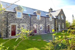 ein großes Backsteinhaus mit Hof in der Unterkunft Pol!cehouse Cottages, Embleton in Alnwick