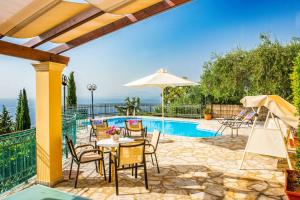 Un patio con mesa y sillas junto a una piscina. en Villa Selini, en Nisakion