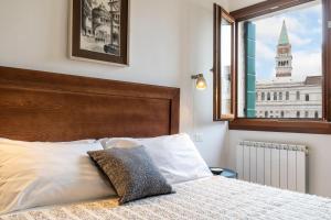 a bed with a wooden headboard and a window at San Marco Schiavoni apartments in Venice
