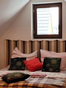 a bed with pillows on top of it with a window at Podhalanka Pokoje in Zakopane