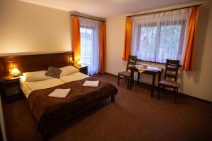 ザコパネにあるWilla Na Szczycieのベッド、テーブル、椅子が備わるホテルルームです。