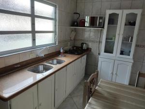 a kitchen with two sinks and a window at Pousada AJS in Palhoça