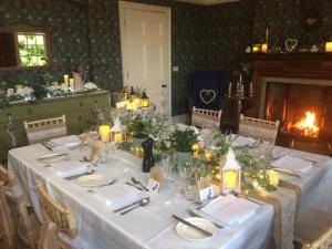 a dining room with a table with white table cloth and a fireplace at Clift Hill in Carlisle