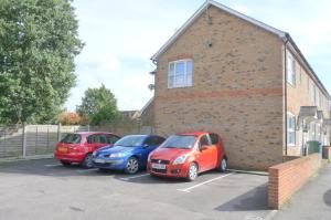 três carros estacionados num parque de estacionamento ao lado de um edifício de tijolos em Friars Walk 2 with 2 bedrooms, 2 bathrooms, fast Wi-Fi and private parking em Sittingbourne