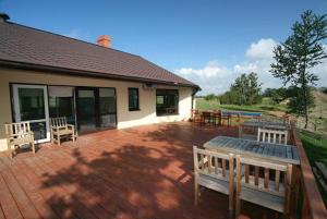 a patio with two benches and a house at Liedags Guesthouse in Jūrkalne