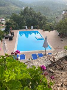 a blue swimming pool with chairs and an umbrella at Villa de Fujacos in Valença +81 photos