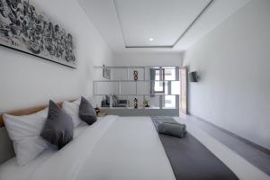 ein Schlafzimmer mit einem großen weißen Bett mit Kissen in der Unterkunft Maisaba Canggu Hotel & Coworking Space in Canggu
