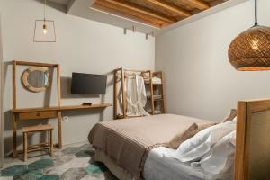 a bedroom with a bed and a desk and a tv at Villas Plumeria in Palaiochora