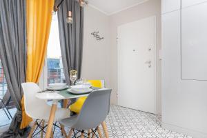 a dining room with a table and yellow chairs at Platinum Tartaczna Apartments by Renters in Gdańsk