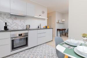 a kitchen with white cabinets and a dining table at Platinum Tartaczna Apartments by Renters in Gdańsk