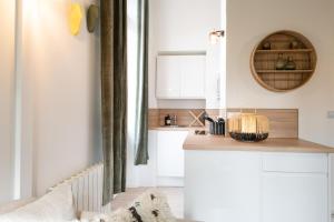 eine Küche mit weißen Schränken und einer hölzernen Arbeitsplatte in der Unterkunft Le Gary - Appartement atypique refait à neuf - A deux pas Parc Tête d'Or in Lyon