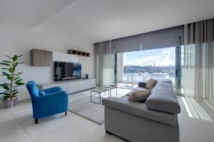 a living room with a couch and a blue chair at Superlative Apartment with Valletta and Harbour Views in Sliema