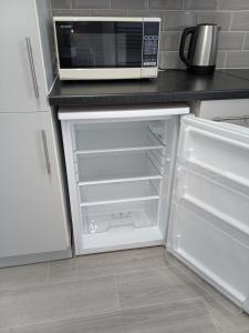 a kitchen with a microwave and an empty refrigerator at St Annes Lodge Apartments, Lytham St Annes in Lytham St Annes