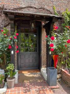 une porte de garage noire avec des fleurs rouges et des roses dans l'établissement Le Moulin Fouret, à Saint-Aubin-le-Vertueux