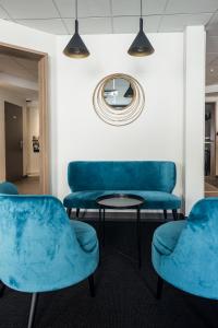 a waiting room with blue chairs and a table at Hôtel des Halles in Dijon
