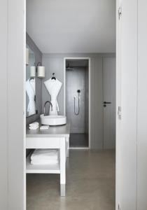 a white bathroom with a sink and a mirror at Hôtel Plage Palace & Spa in Palavas-les-Flots