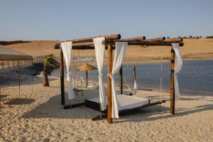 uma cama de dossel numa praia de areia com água em Monte Vale - Organic Farm em Entradas