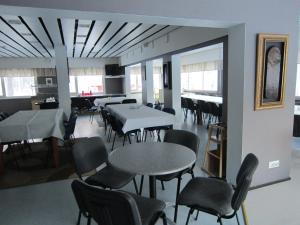 a dining room with tables and chairs and windows at Hostelli Kuninkaankartano in Kuninkaanlähde