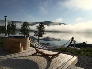 a hammock sitting on a deck next to a lake at Arctic Land Adventure Glass Igloos in Kilpisjärvi