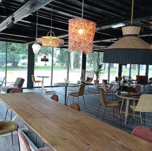 una sala da pranzo con tavoli, sedie e lampadari a braccio di Hôtel le Corbusson a Saint-Berthevin-sur-Vicoin