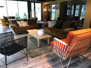 a living room with couches and a table and chairs at Hôtel le Corbusson in Saint-Berthevin