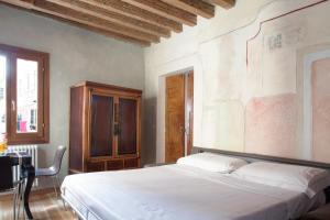 Un dormitorio con una cama blanca y un armario de madera. en Scala Mata, en Venecia