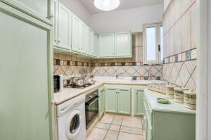 una cucina con armadi verdi e una lavatrice/asciugatrice di Appartamento Potì sulla spiaggia a Porto Cesareo