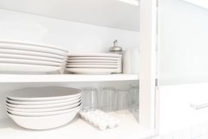 ein weißer Schrank mit Platten und Schalen auf einem Regal in der Unterkunft nJoy! Sunny & Simple - Dachterasse - gratis WLAN in Bad Friedrichshall