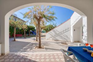 un arco sopra un patio con tavolo e albero di Appartamento Potì sulla spiaggia a Porto Cesareo