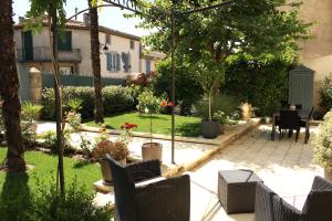 a garden with a patio with chairs and a table at La Glycine Blanche in Pomas