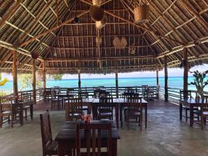 a restaurant with tables and chairs and a view of the ocean at Promised Land Lodge in Kizimkazi