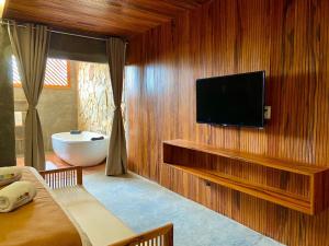 a bathroom with a tub and a television on a wall at Hotel Casa do Mar in Icapuí