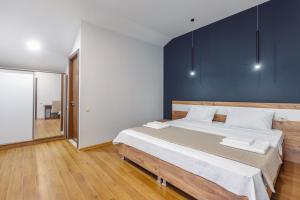 1 dormitorio con 1 cama grande y pared azul en 10 KEYS Boutique Hotel en Borjomi