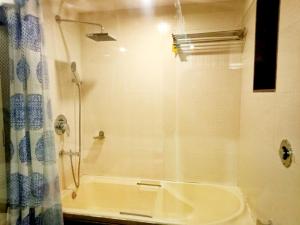 a bathroom with a shower and a tub with a curtain at Hotel Poonam in Mahabaleshwar
