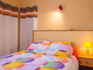 a bed with a colorful comforter in a bedroom at Gîte Rouans, 2 pièces, 4 personnes - FR-1-306-830 in Rouans