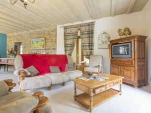 ein Wohnzimmer mit einem roten Sofa und einem TV in der Unterkunft Gîte Guémené-Penfao, 4 pièces, 6 personnes - FR-1-306-1107 in Guéméné-Penfao
