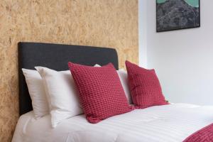 Una cama con almohadas rojas y blancas. en On The Walk, en Edimburgo
