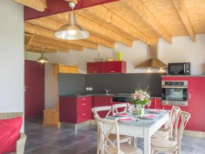 une cuisine avec des placards rouges et une table avec des chaises dans l'établissement Gîte Nort-sur-Erdre, 3 pièces, 5 personnes - FR-1-306-1145, à Nort-sur-Erdre