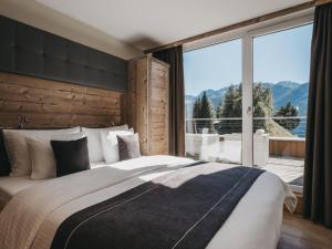 ein Schlafzimmer mit einem großen Bett und einem großen Fenster in der Unterkunft VAYA Terrazena Serfaus in Serfaus