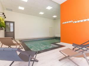 una piscina in una stanza con sedie e una parete arancione di Gîte Château-Thébaud, 5 pièces, 10 personnes - FR-1-306-913 a Châteauthébaud